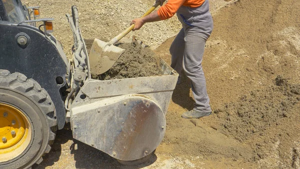 AFSLUITEN: Werknemer gebruikt een schop om betonmenging achterin een bulldozer te mengen — Stockfoto