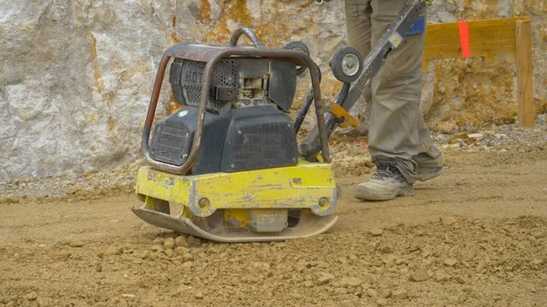 CERRAR UP El hombre utiliza la máquina de nivelación manual para preparar el terreno para el vertido de mortero —  Fotos de Stock