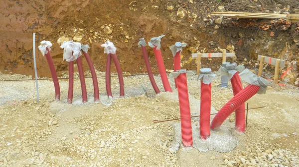 ZAMKNIJ: Długie czerwone przewody plastikowe trzymać w powietrzu z ziemi żwiru — Zdjęcie stockowe