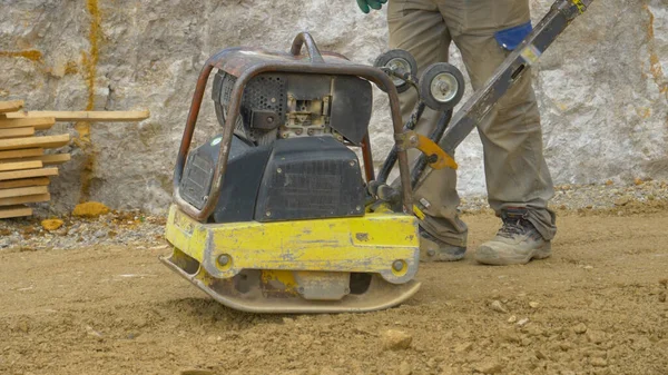 CLOSE UP: ratelende zware egalisatie machine pond de grind grond. — Stockfoto