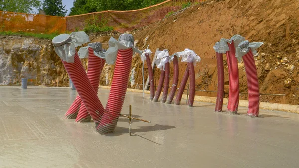 CLOSE UP: Corrugated red and grey piping sticks out of drying house foundation. — Stock Photo, Image