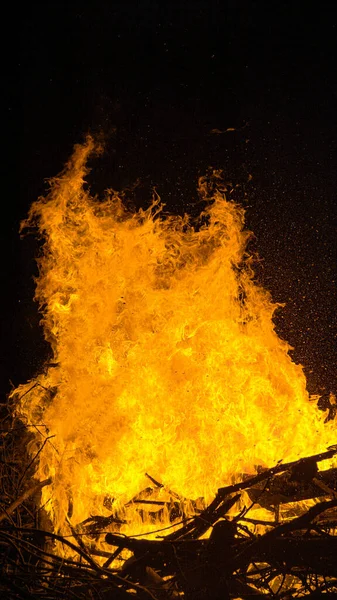 VERTIKEL: Auf einem beschaulichen Campingplatz geht ein Haufen Brennholz in Flammen auf. — Stockfoto