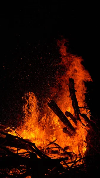 VERTICAL: Ohnivé plameny pohltí hromadu suchých větví a větviček na dvorku. — Stock fotografie