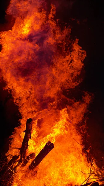 VERTICAL: A pile of thick branches and twigs bursts up into flames at midnight. — Stock Photo, Image