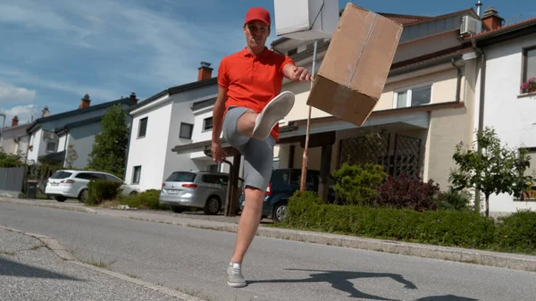 LOW ANGLE: Careless young courier kicking customers' orders at their doorsteps. — Stock Photo, Image