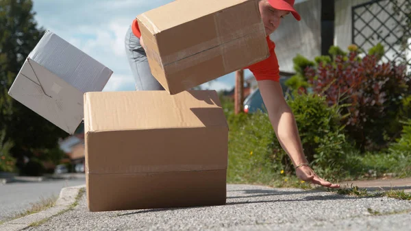 CLOSE UP: Clumsy delivery man falls to the ground and drops cardboard boxes — Stock Photo, Image