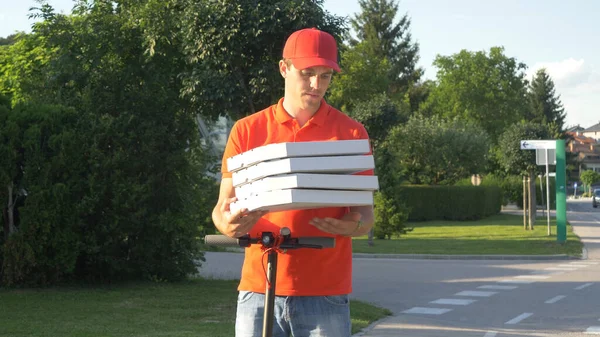 Genç kurye e-scooterla teslim etmeden önce pizza kutularını tutuyor. — Stok fotoğraf