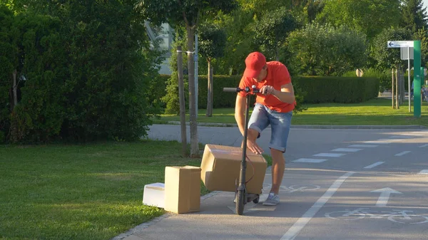 Postman stacks three boxes on his electric scooter while delivering packages. — Stock Photo, Image