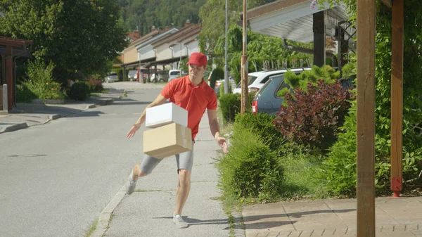 Delivery guy kicks packages in someone's driveway on a sunny day in the suburbs. — Stock Photo, Image