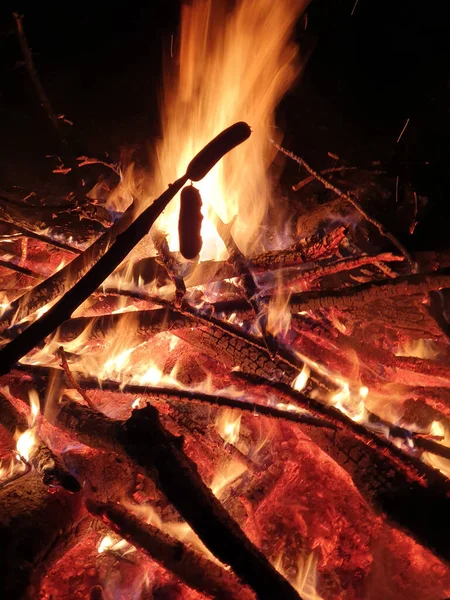 CLOSE UP: Würstchen braten über loderndem Lagerfeuer, das um Mitternacht brennt. — Stockfoto