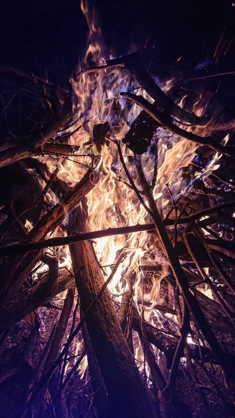 VERTIKEL: Auf einem beschaulichen Campingplatz geht ein Haufen Brennholz in Flammen auf. — Stockfoto