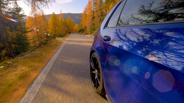 CLOSE UP: Cinematic shot van blauwe sportscar verlaten van een schilderachtige bergweg achter — Stockfoto