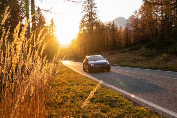 CERRAR: Coche turístico conduce por una carretera de montaña en el pintoresco atardecer dorado. — Foto de Stock