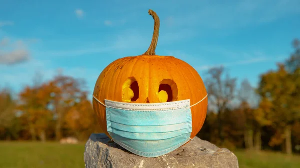 CLOSE UP: Corona conscious orange Halloween pumpkin wearing medical face mask