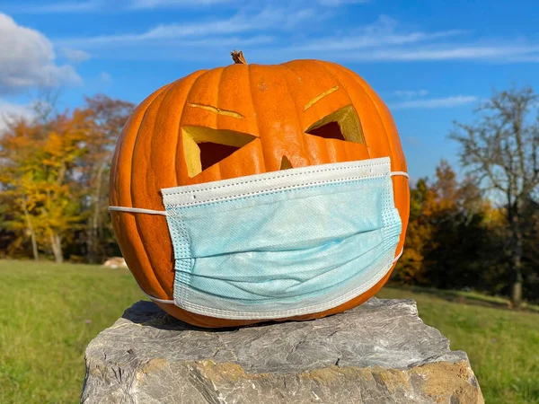 PORTRAIT: Gran decoración de calabaza naranja con una mascarilla médica en Halloween —  Fotos de Stock