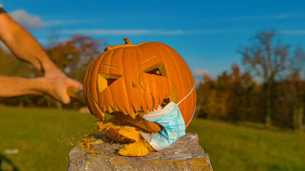 Calabaza con mascarilla de Coronavirus siendo aplastada con bate en Halloween —  Fotos de Stock