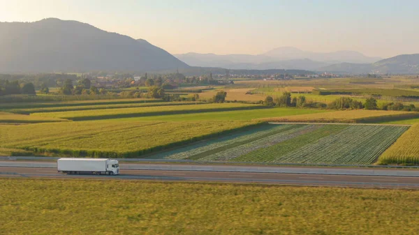 COPY SPACE: Semi-caminhão transporta mercadorias através de uma rodovia que atravessa o campo. — Fotografia de Stock