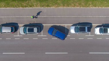 Kişi arabasını dar bir yol kenarına paralel park etmeye çalışır..