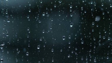 Şiddetli bir yağmur fırtınası sırasında pencere camında temiz yağmur damlaları birikir..