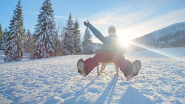 Aktif kış tatilindeki genç bir kadın güneşli bir günde kızakla kayıyor..