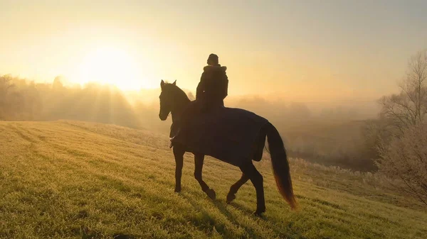 Zlaté sluneční paprsky nakukují mlhou pro jezdce na koních, aby prozkoumali krajinu. — Stock fotografie