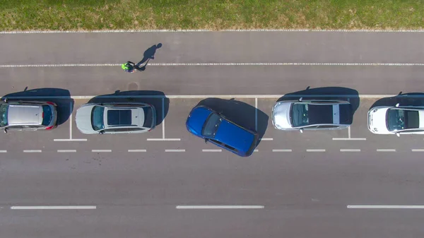 Kişi arabasını dar bir yol kenarına paralel park etmeye çalışır..