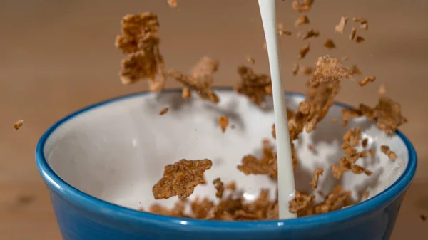 MACRO Milk and granola are poured into a bowl and combined for healthy breakfast — Stock Photo, Image