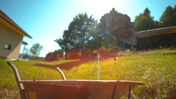 CSOPORT UP: Az udvarban dolgozó személy a kerttől talicskáig lapátolja a földet. — Stock Fotó