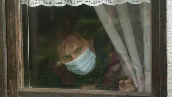 CERRAR: La señora solitaria observa ansiosamente el vecindario en medio de una pandemia. —  Fotos de Stock