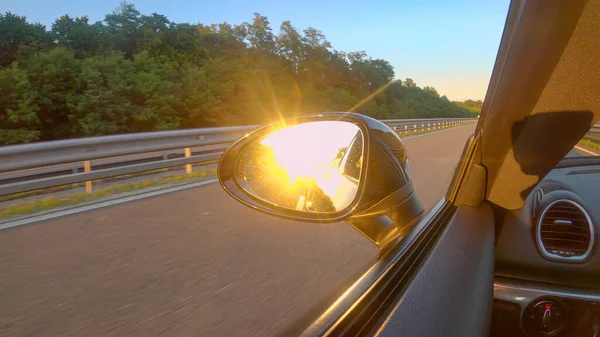 CHIUSURA: raggi di sole dorati accecanti si riflettono nello specchio laterale di un'auto. — Foto Stock