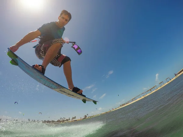 COPY szóköz: fiatal férfi turista ugrik a levegőben, miközben kitesurfing egy napsütéses napon — Stock Fotó