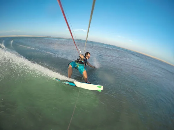 Atlético turista masculino hace una mano arrastre a lo largo de la superficie del agua mientras kitesurf —  Fotos de Stock