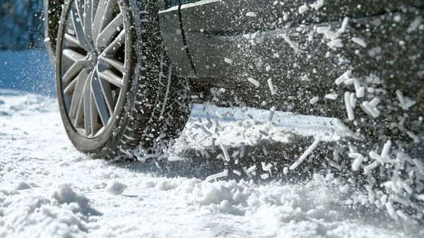Kar yığınları havada uçuşuyor, araba karlı bir yolda ilerlemeye çalışırken.. — Stok fotoğraf