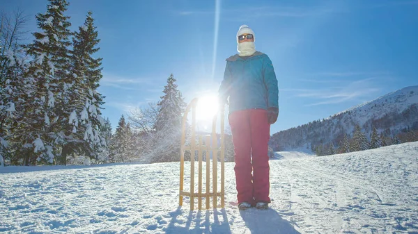 在Kranjska Gora的一个有趣的日子里，年轻的女人站在她的雪橇旁边. — 图库照片