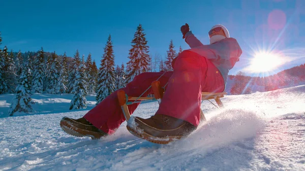 LENS FLARE: radosna kobieta zjeżdża ze śnieżnego wzgórza w słonecznych słoweńskich górach. — Zdjęcie stockowe