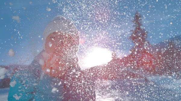 PORTRAIT: Mujer joven sopla en su mano llena de nieve y se vuelve hacia la cámara. — Foto de Stock