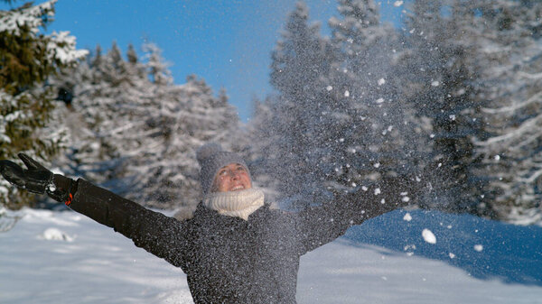 CLOSE UP: Веселая туристка глотает горсть свежего снега в воздухе.