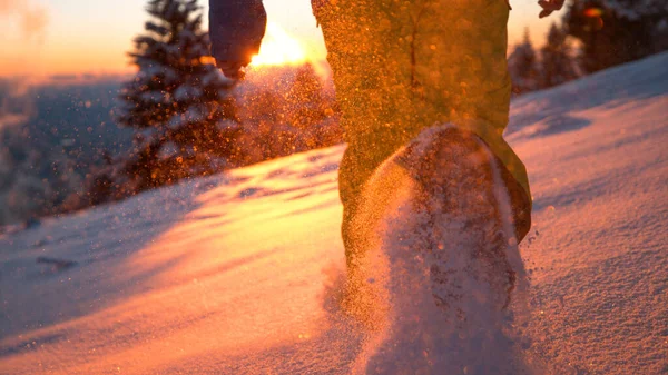 LOW ANGLE: Płatki śniegu lśnić jak człowiek biegnie wzdłuż zaśnieżonej łąki o zachodzie słońca. — Zdjęcie stockowe