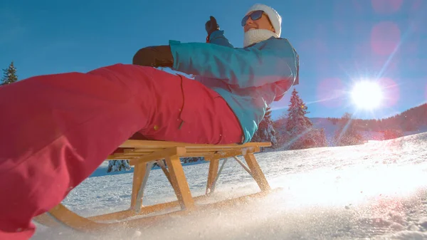 LOW ANGLE: Wesoła kobieta na wakacjach w Kranjskiej Górze zjeżdża ze śnieżnego wzgórza. — Zdjęcie stockowe