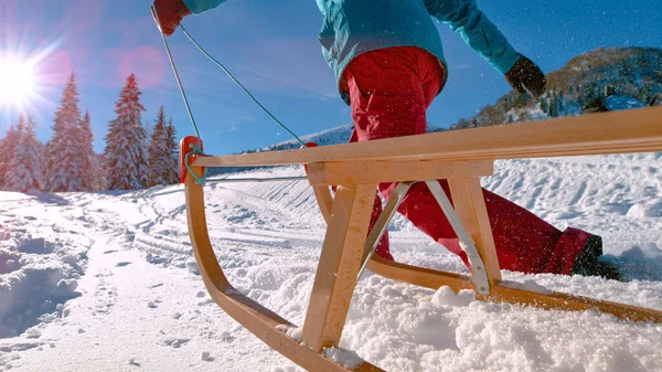 ÁNGULO BAJO: Mujer joven corre con entusiasmo a lo largo de una pendiente de nieve durante el viaje en trineo. — Foto de Stock