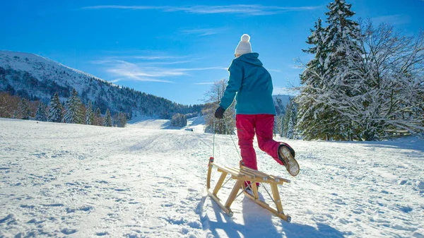 无法辨认的女人骑着雪橇跑上了空旷的雪山. — 图库照片