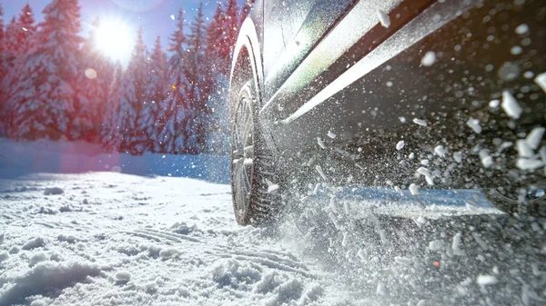 Parlak güneş ışınları karda yol tutuşu kazanmak için mücadele eden arabanın üzerinde parlıyor.. — Stok fotoğraf