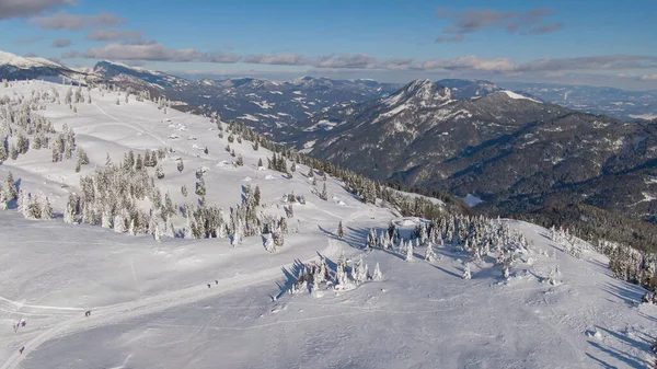 DRONE: Vliegen over besneeuwde heuvels van Velika Planina en naar een groene vallei. — Stockfoto