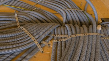 Gri kıvrımlı pvc tüpleri ahşap bir evin zemininden geçiyor..