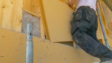 Müteahhit, izolasyon panellerini selülozla dolu bir duvara yerleştirir..