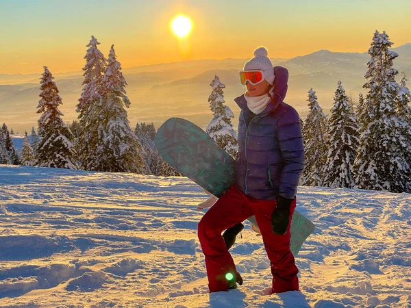 CERRAR: El sol dorado de la mañana de invierno se eleva por encima de la montaña y el snowboarder senderismo. — Foto de Stock