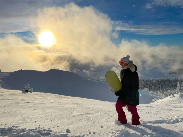 Νέος θηλυκός snowboarder περπατά σε χιονισμένο λιβάδι σε μια ηλιόλουστη μέρα. — Φωτογραφία Αρχείου