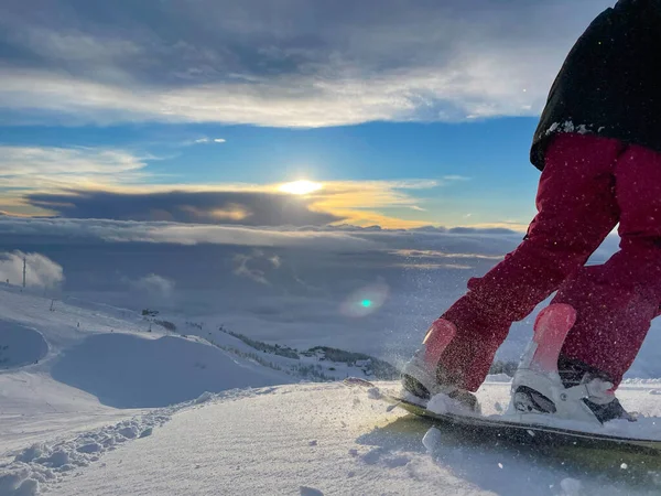 ANGOLO BASSO: lo snowboarder femminile scende su piste sterrate vicino a una stazione sciistica. — Foto Stock