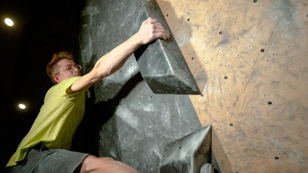 FERMER : Un jeune homme athlétique saisit une prise de volume noire en grimpant à l'intérieur. — Photo