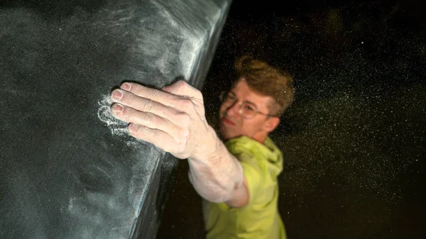 FECHAR-se: Jovem alpinista do sexo masculino atinge e aperta um volume preto áspero segurar. — Fotografia de Stock
